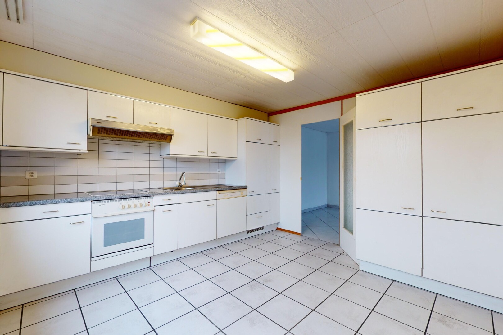 cuisine avec carrelage, four, hotte, crédence, et meubles blancs