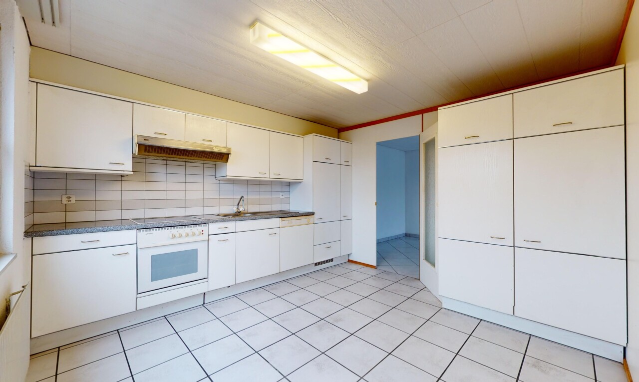 cuisine avec carrelage, four, hotte, crédence, et meubles blancs
