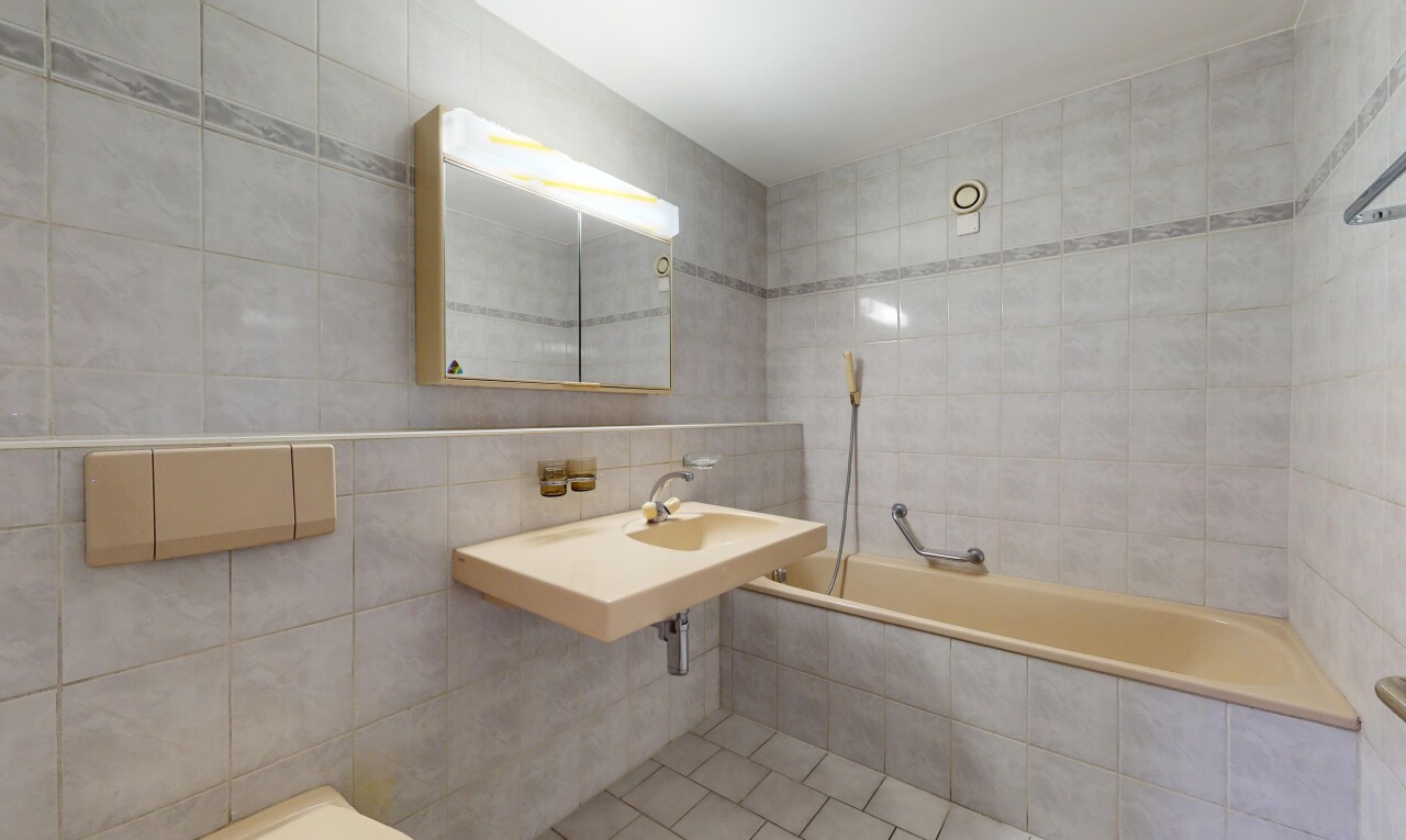 salle de bains avec miroir, mur carrelé, vasque, et baignoire