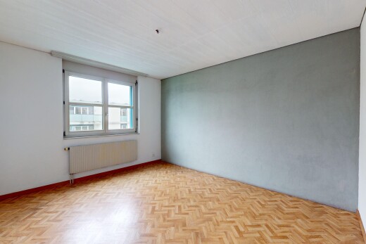 pièce vide avec parquet, radiateur, et lumière naturelle