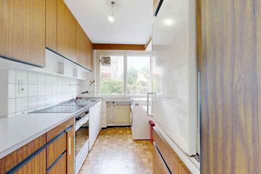 kitchen featuring light countertops, light flooring, backsplash, dual tone cabinetry, and radiator heating unit