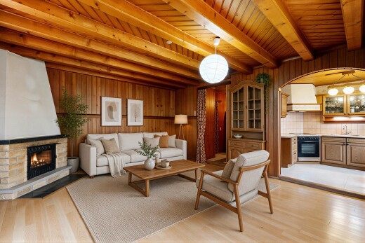 living area with light wood-style flooring, wood walls, a stone fireplace, a wood ceiling with exposed beams, and arched walkways
