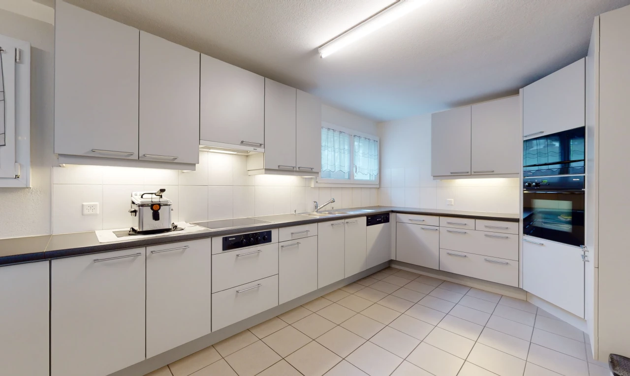 cuisine avec lumière naturelle, carrelage, four, cuisinière électrique, sol clair, et meubles blancs