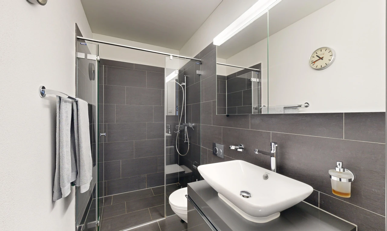 salle de bains avec vasque, mur carrelé, miroir, crédence, et toilettes