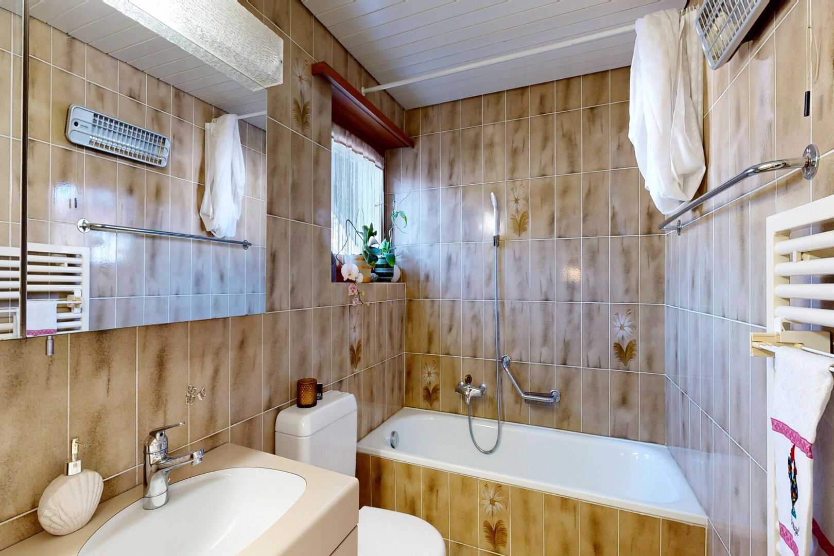 salle de bains avec chauffe-serviettes, tile wall, mur en carrelage, miroir, et salle de bain complète