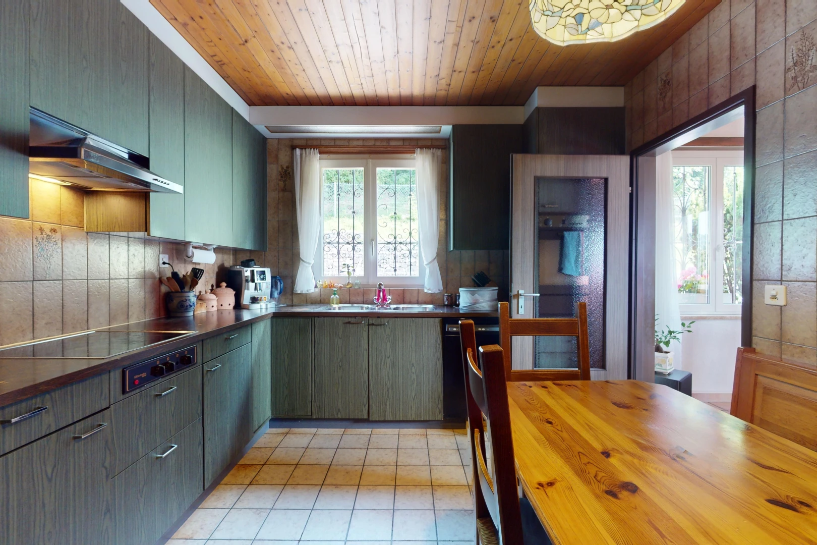 cuisine avec cuisinière, hotte, lumière naturelle, et plafond de bois