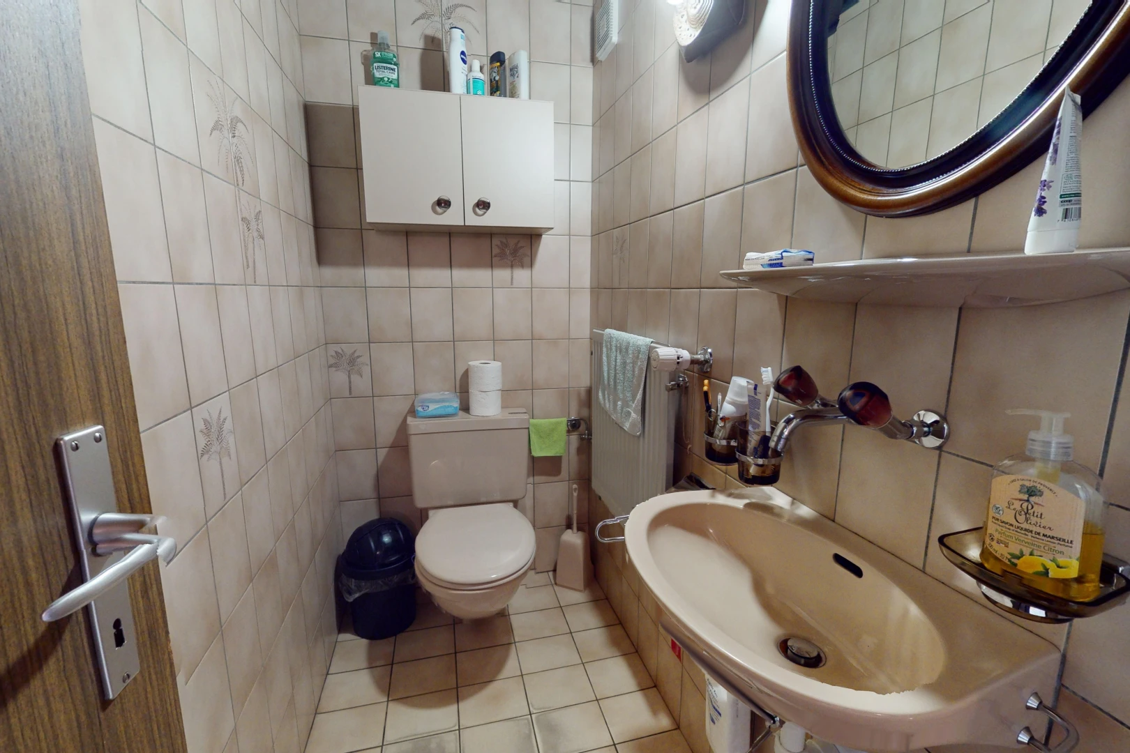salle de bains avec carrelage, miroir, toilettes, et mur carrelé