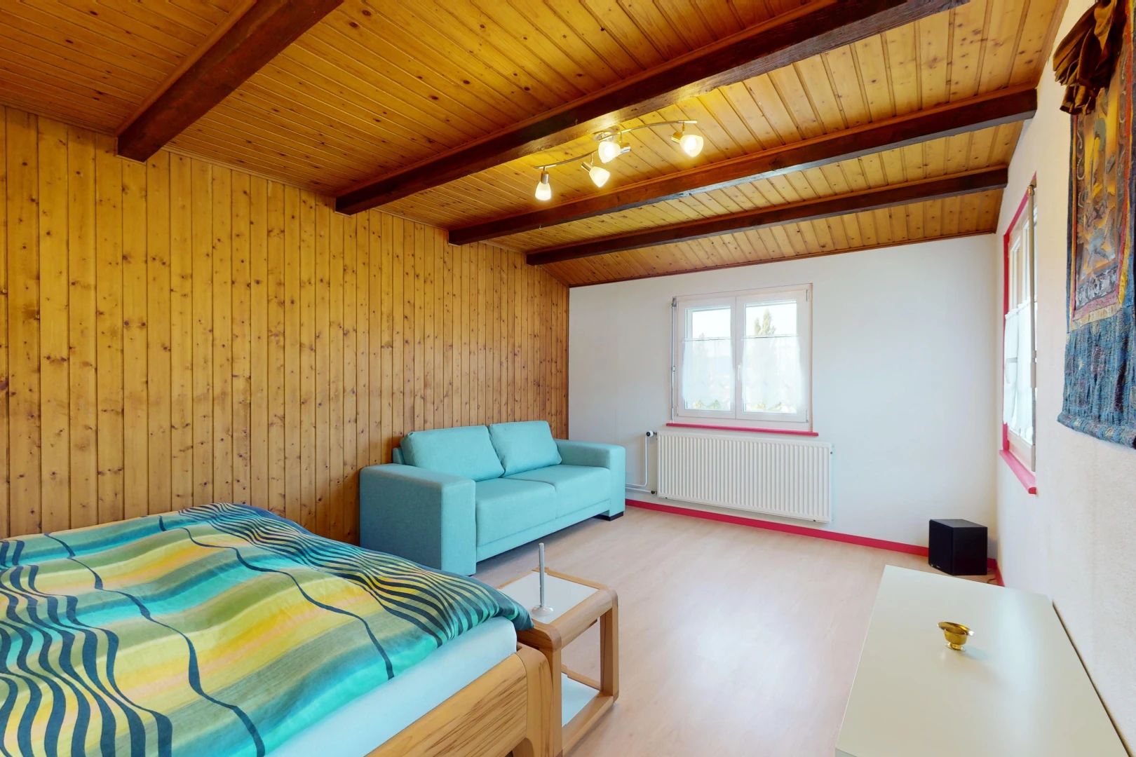 chambre avec radiateur, poutres apparentes, lumière naturelle, et plafond de bois
