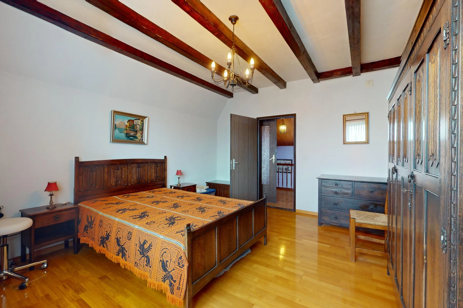 chambre avec plancher de bois, lustre, poutres apparentes, et plafond voûté