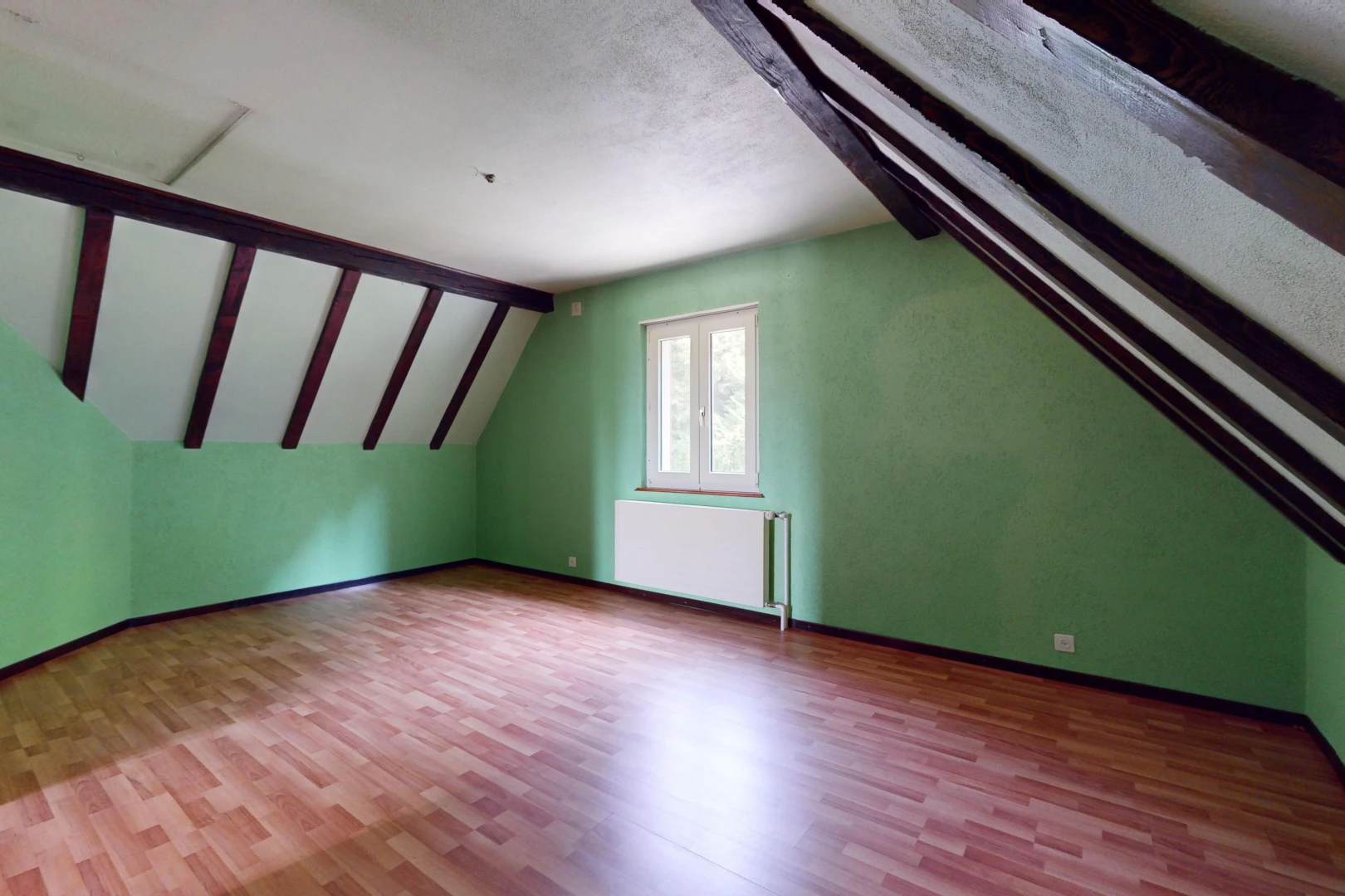 pièce vide avec plafond voûté, lumière naturelle, plafond en crépis, plancher de bois, et radiateur