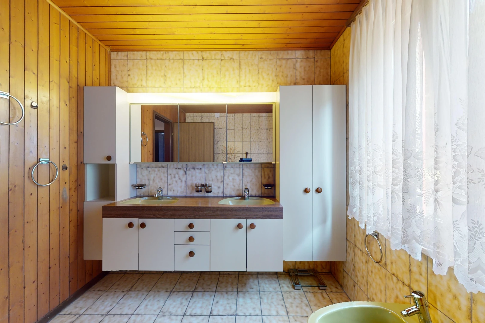 salle de bains avec mur en bois, vasque, miroir, meuble-lavabo, et plafond de bois
