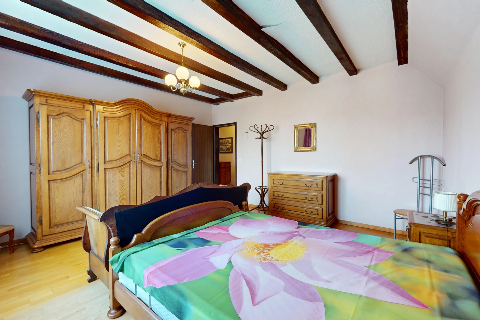 chambre avec plancher de bois, lustre, et poutres apparentes