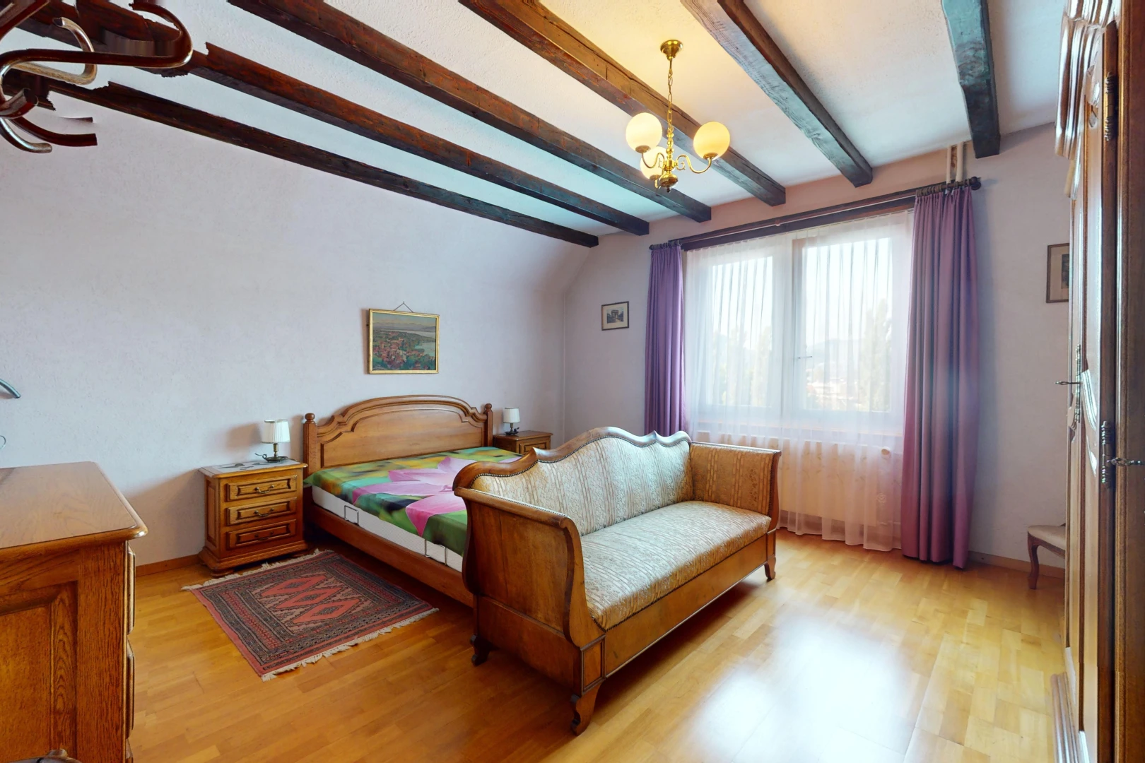 chambre avec lustre, plancher de bois, poutres apparentes, et lumière naturelle