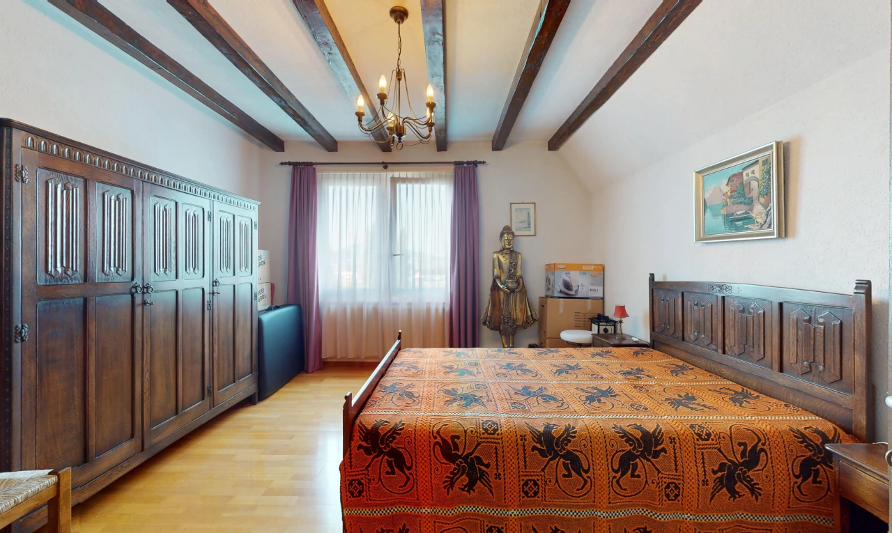 chambre avec lustre, plancher de bois, poutres apparentes, lumière naturelle, et plafond voûté