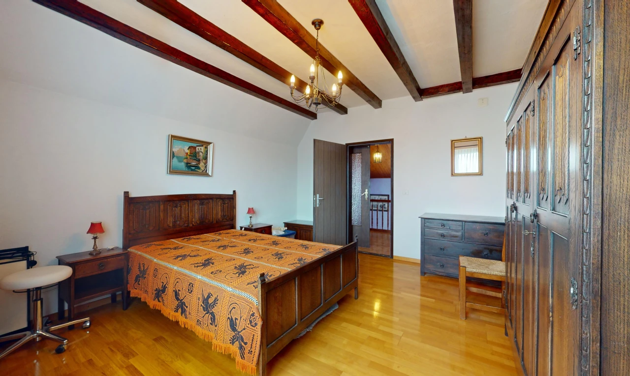 chambre avec plancher de bois, lustre, poutres apparentes, et plafond voûté