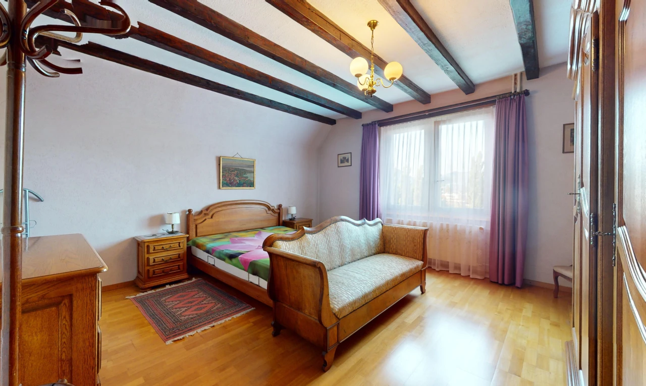 chambre avec lustre, plancher de bois, poutres apparentes, et lumière naturelle