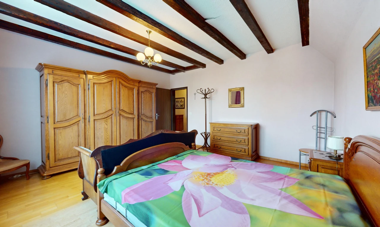 chambre avec plancher de bois, lustre, et poutres apparentes