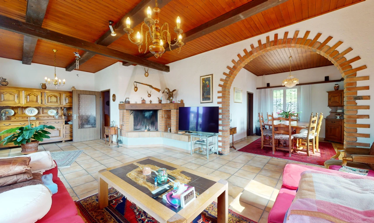 salon / salle à manger avec carrelage, lumière naturelle, télévision, passerelles voûtées, et poutres apparentes