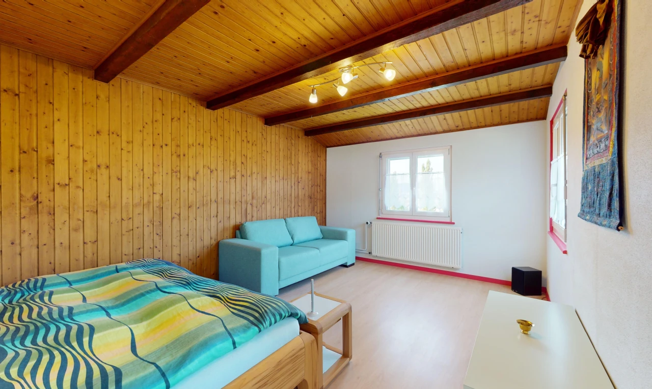 chambre avec radiateur, poutres apparentes, lumière naturelle, et plafond de bois