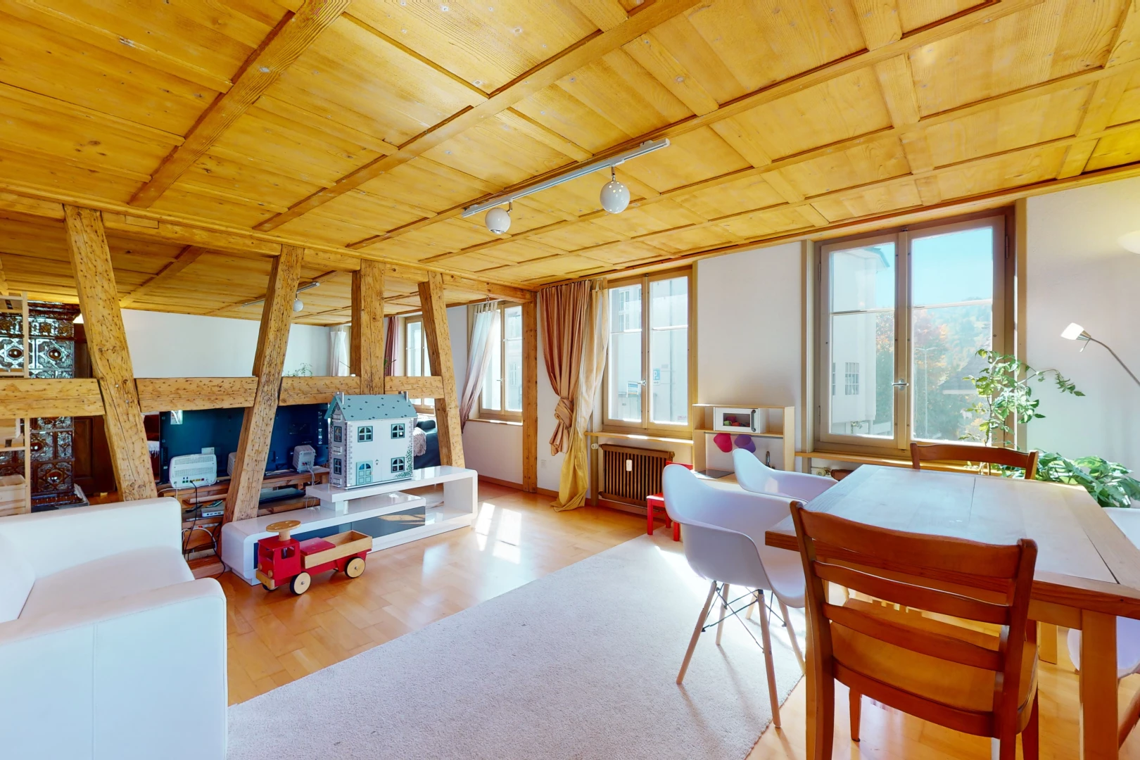 salle à manger avec lumière naturelle, poutres apparentes, parquet, et radiateur