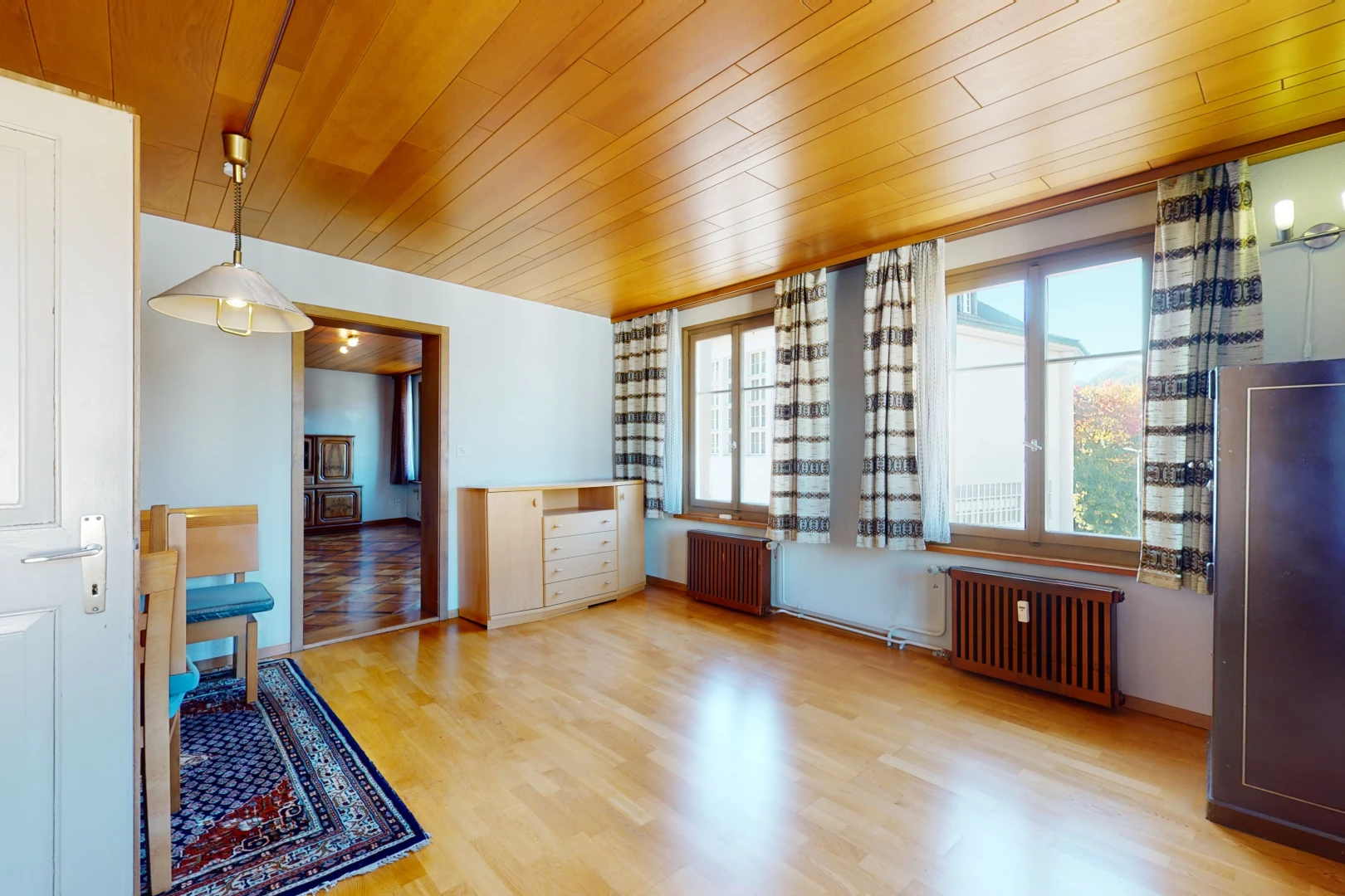 chambre vide avec lumière naturelle, parquet, et radiateur