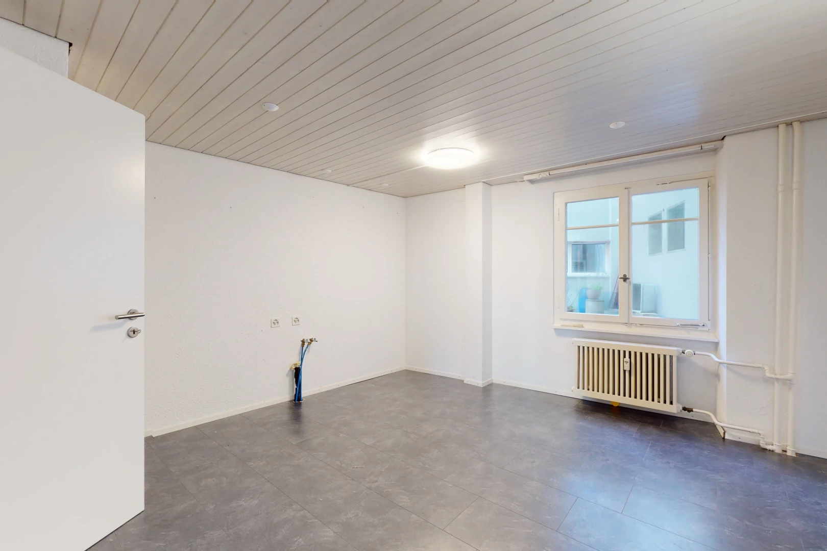 chambre vide avec lumière naturelle, carrelage, et radiateur