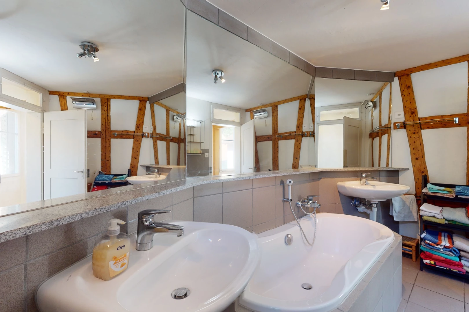 salle de bains avec lumière naturelle, miroir, double vasque, et baignoire