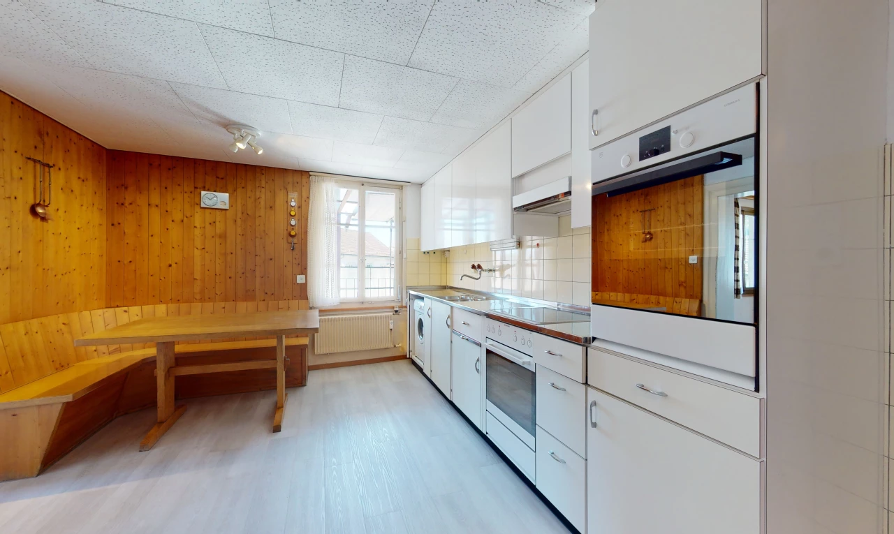cuisine avec lumière naturelle, cuisinière électrique, four, radiateur, hotte, sol clair, et meubles marron
