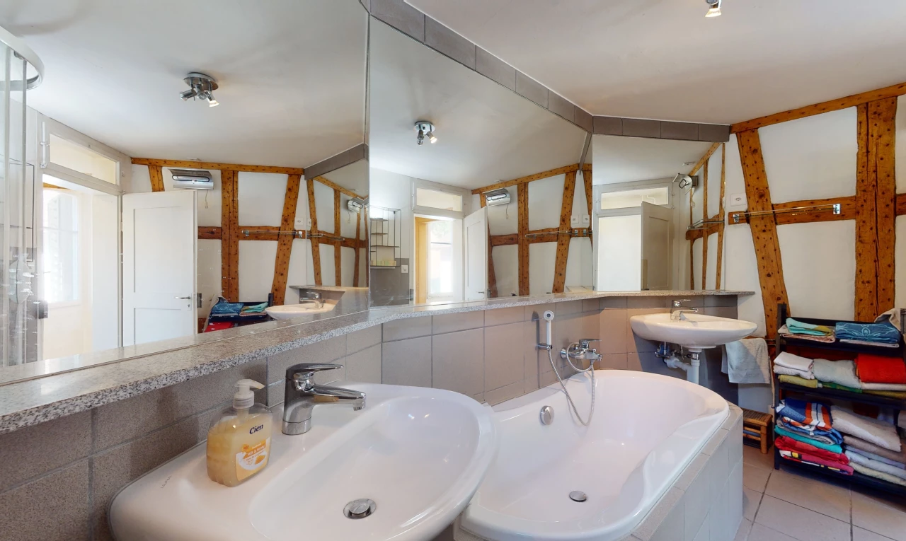salle de bains avec lumière naturelle, miroir, double vasque, et baignoire