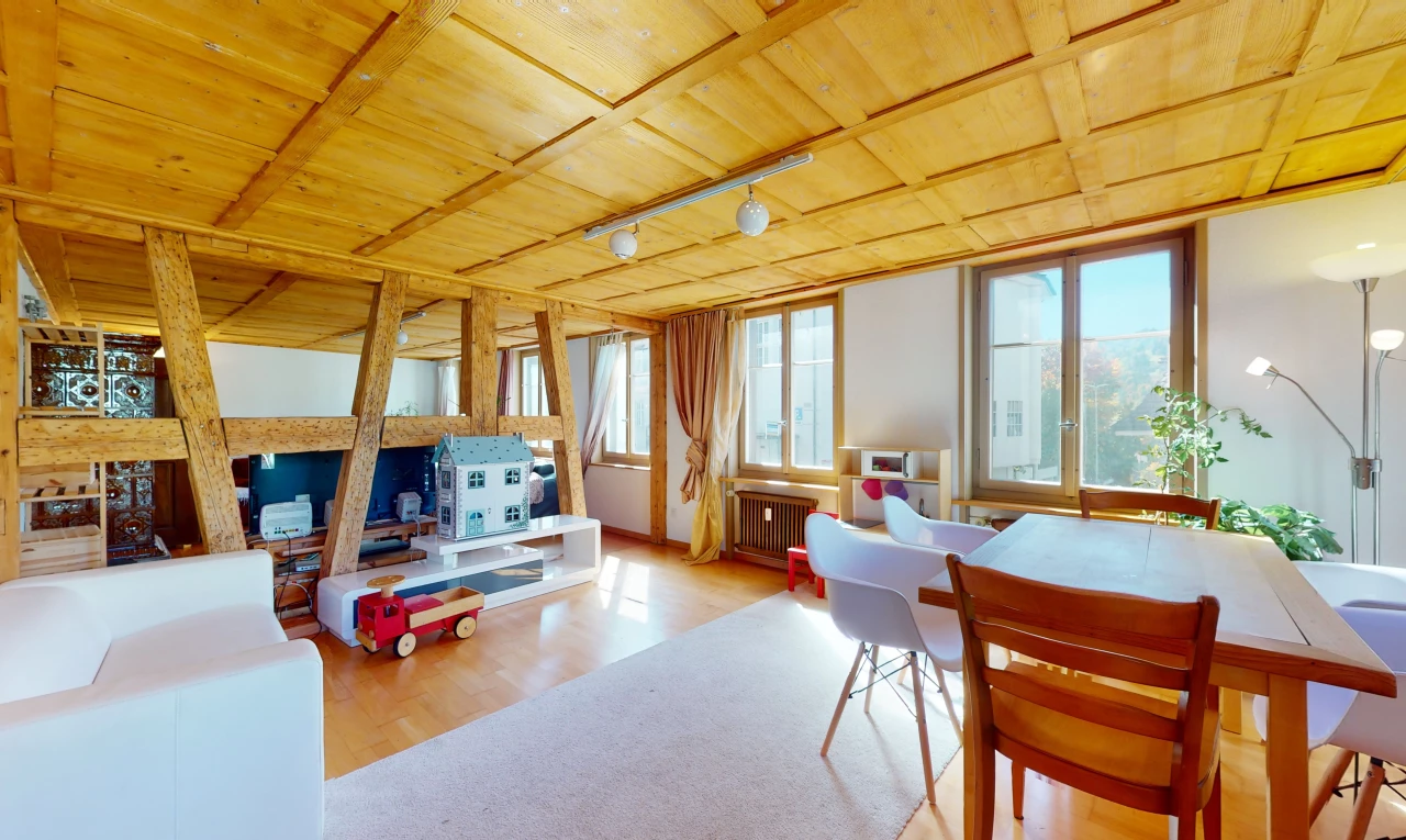 salle à manger avec lumière naturelle, poutres apparentes, parquet, et radiateur