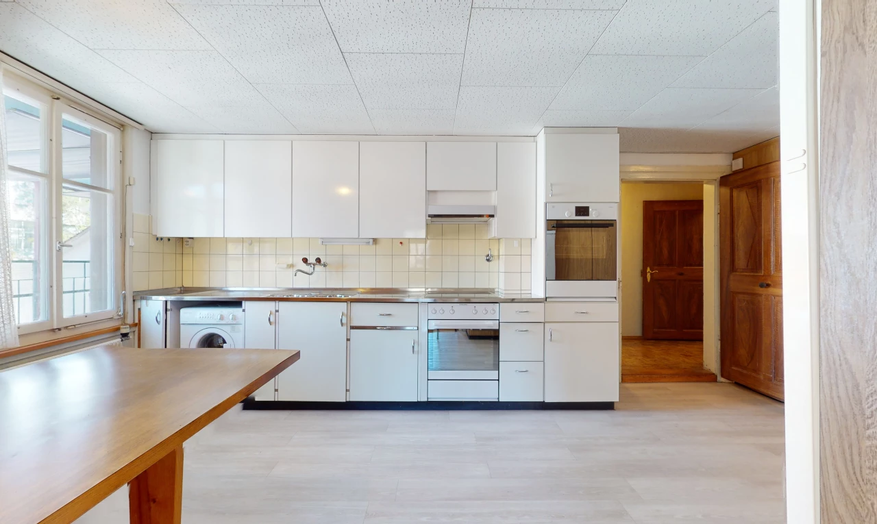 cuisine avec parquet, lumière naturelle, machine à laver / sèche-linge, four, sol clair, et meubles blancs