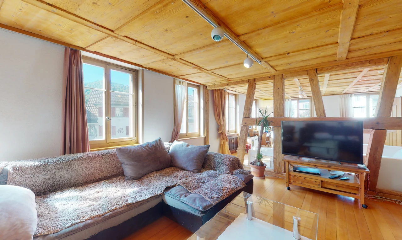 salon avec poutres apparentes, parquet, lumière naturelle, et télévision