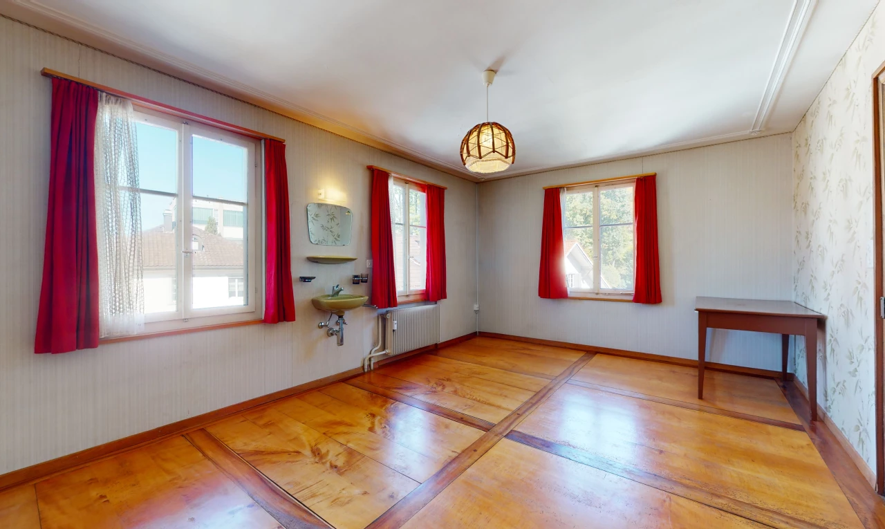 chambre vide avec parquet, lumière naturelle, et radiateur