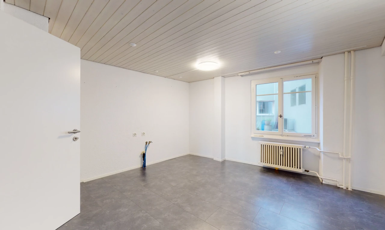 chambre vide avec lumière naturelle, carrelage, et radiateur