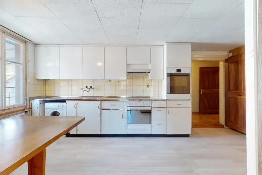cuisine avec parquet, lumière naturelle, machine à laver / sèche-linge, four, sol clair, et meubles blancs