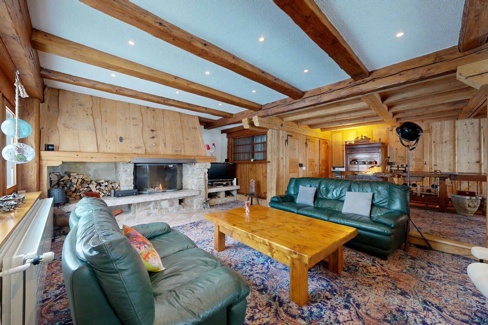 salon avec mur en bois, wood wall, plafond à poutres, beamed ceiling, et cheminée