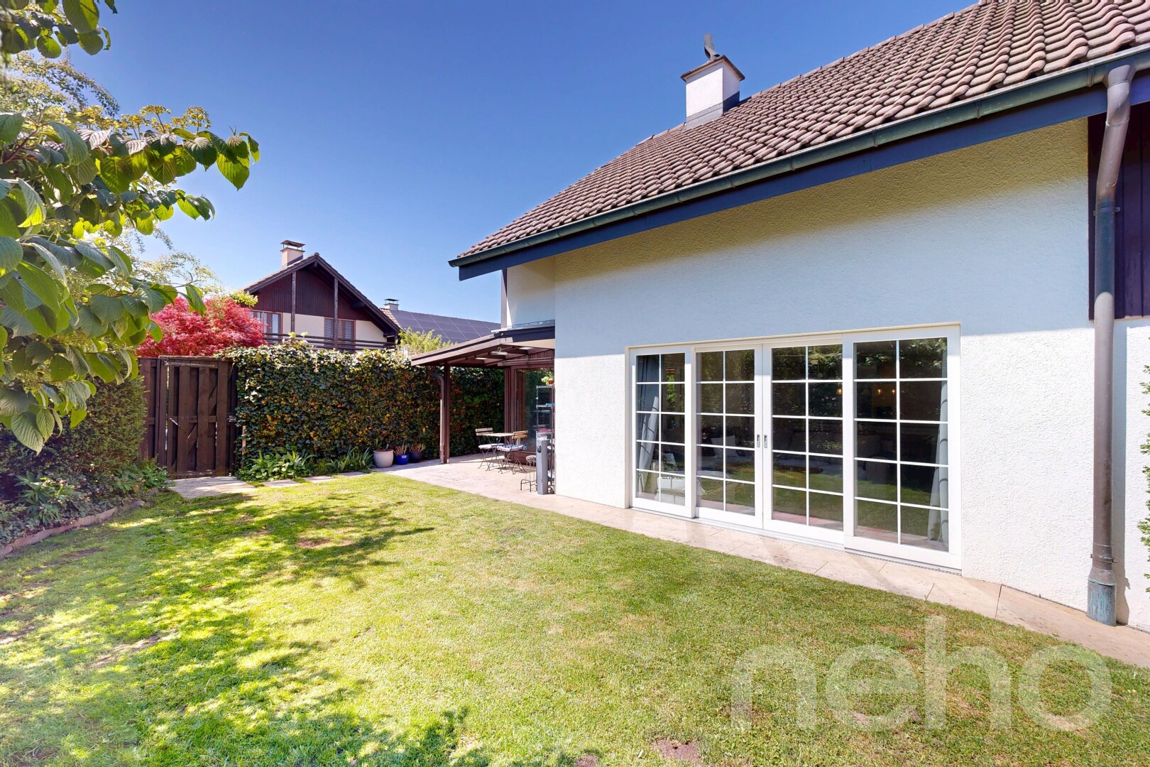 outdoor house with stucco siding, a patio area, a chimney, and a tiled roof