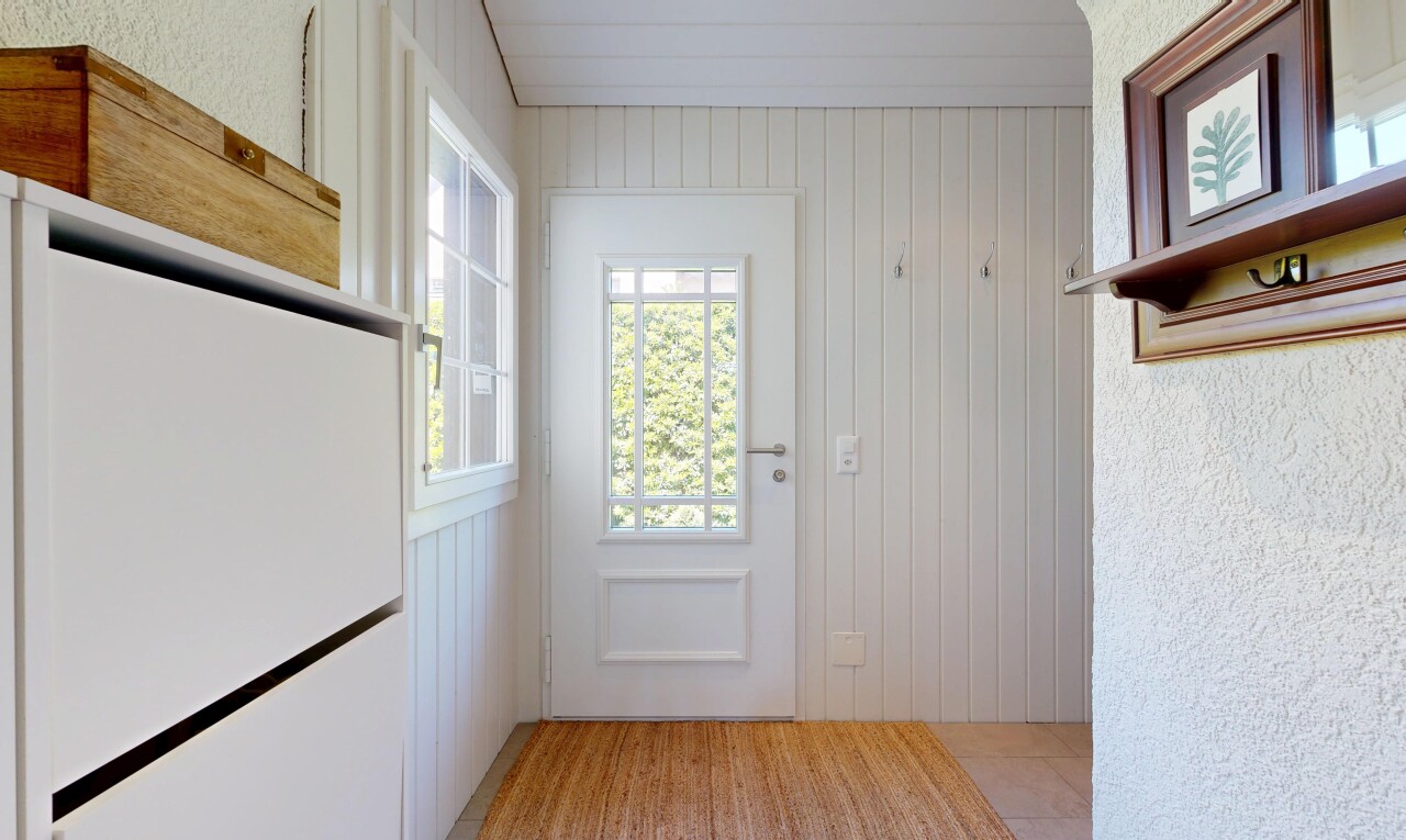 hall with light wood-type flooring and wooden walls