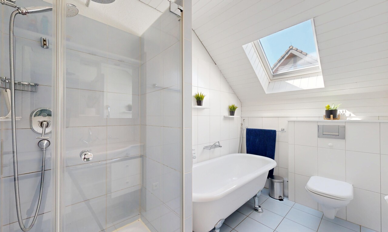 full bathroom featuring a skylight, lofted ceiling, tile walls, a shower stall, and light tile patterned floors