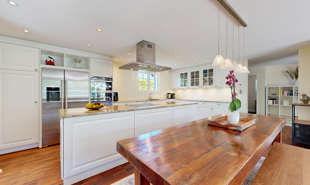 kitchen with white cabinetry, a center island, stainless steel appliances, light stone countertops, and glass insert cabinets