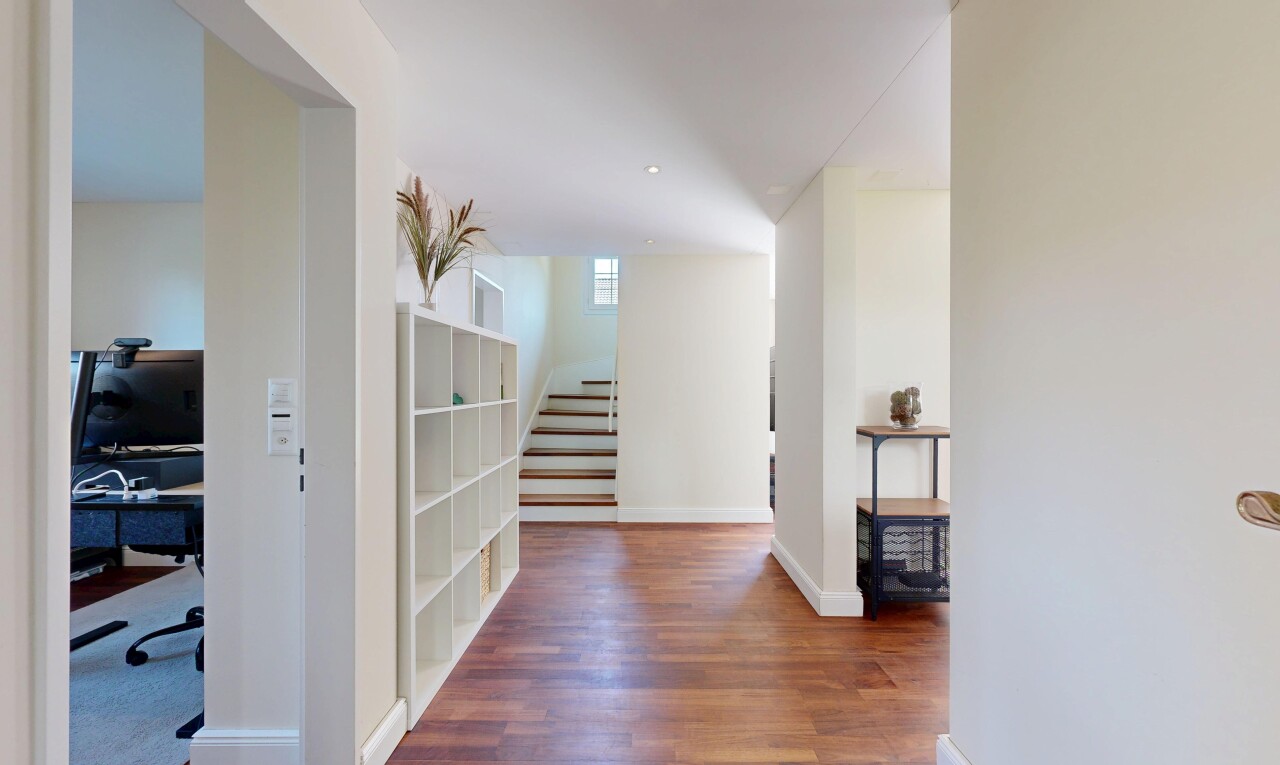 corridor featuring dark wood-style floors and a desk
