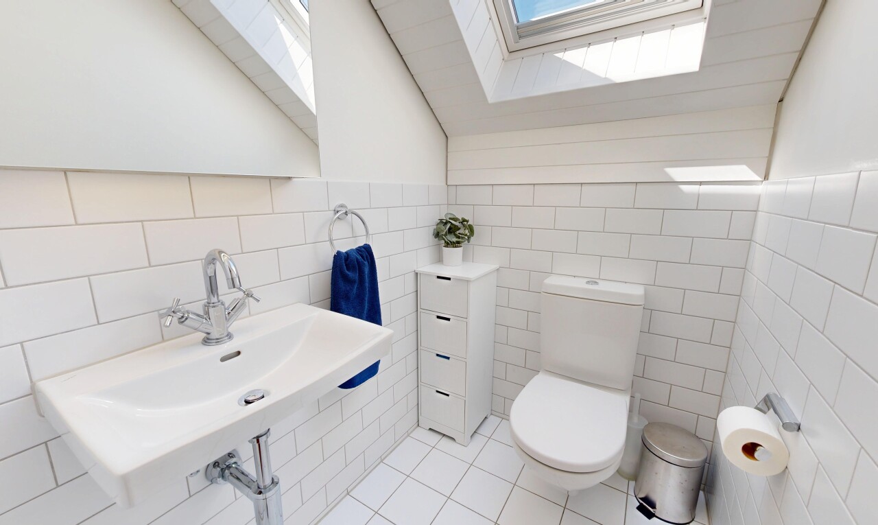 half bathroom with a skylight, vaulted ceiling, tile walls, and light tile patterned floors