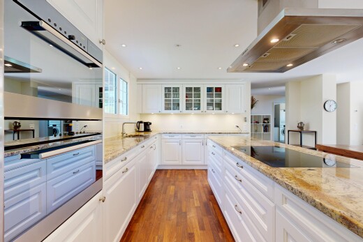 küche mit doppel backofen, dunstabzugshaube, stone countertops, stein arbeitsplatten, und white cabinets