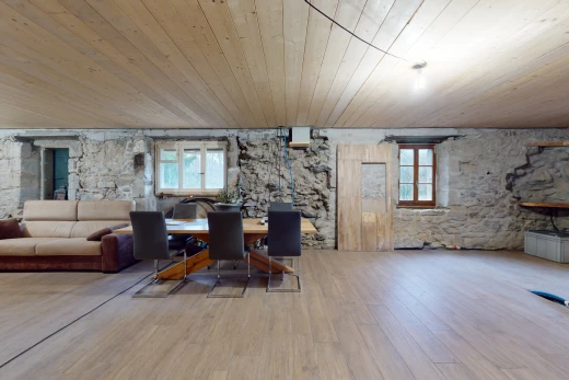 salon / salle à manger avec plafond de bois, lumière naturelle, mur en pierre, et plancher de bois