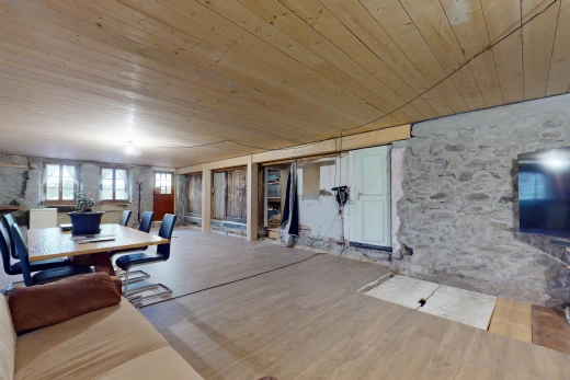 salon avec lumière naturelle, plafond de bois, mur en pierre, télévision, et plancher de bois