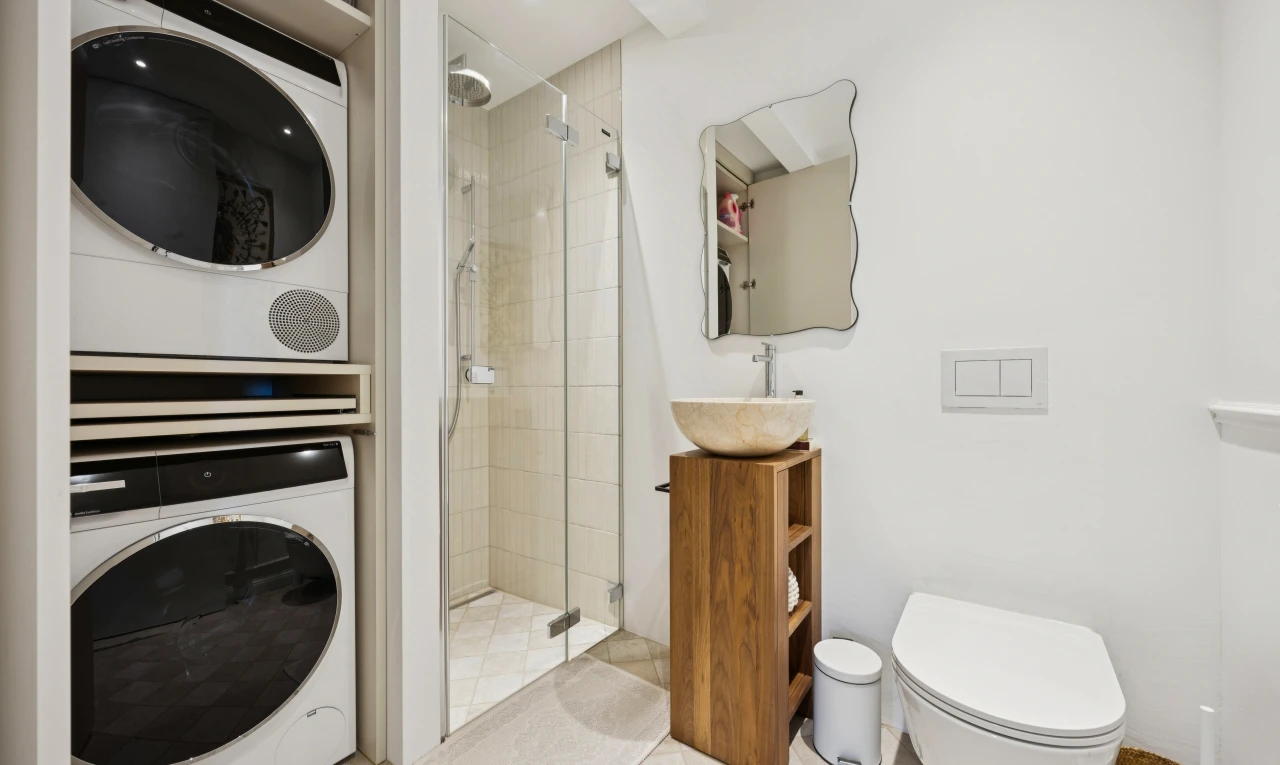 salle de bains avec douche, salle de bain complète, miroir, lave-linge et sèche-linge superposés, et drywall