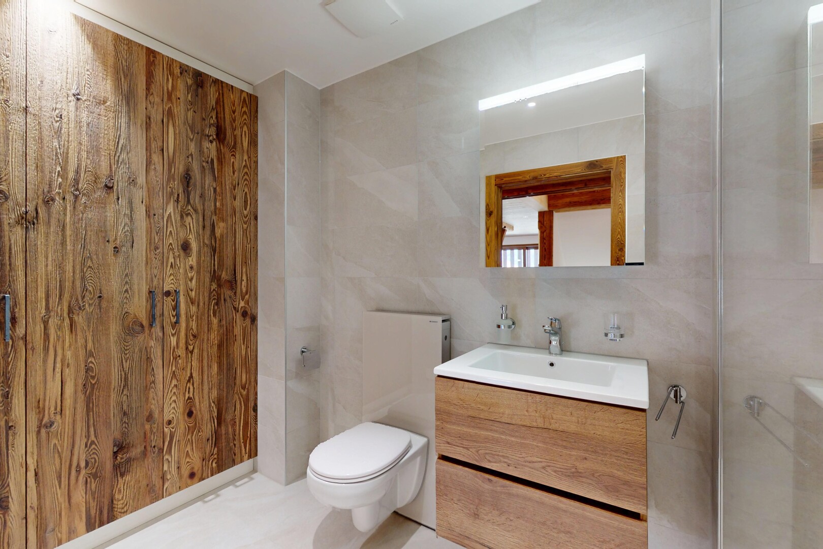 salle de bains avec évier, lavabo (ou coiffeuse selon le contexte), toilette, mur en carrelage, et miroir