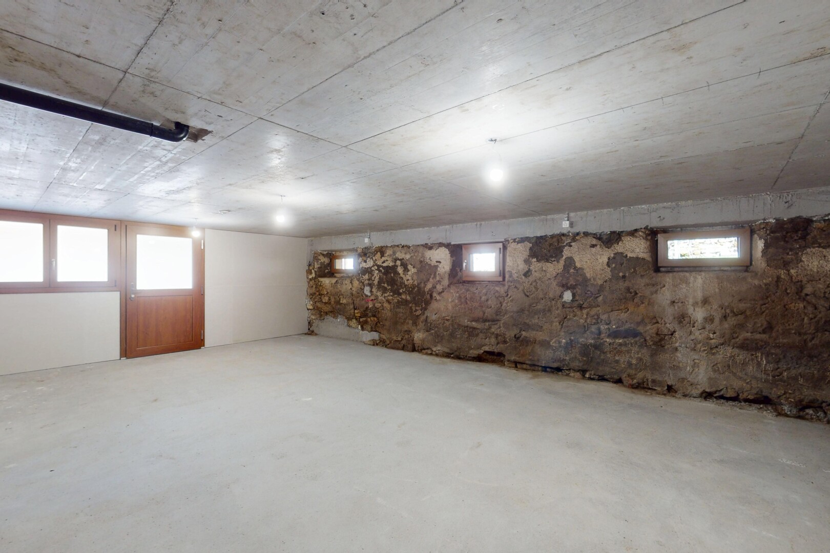 pièce vide avec sous-sol, sol en béton, et lumière naturelle