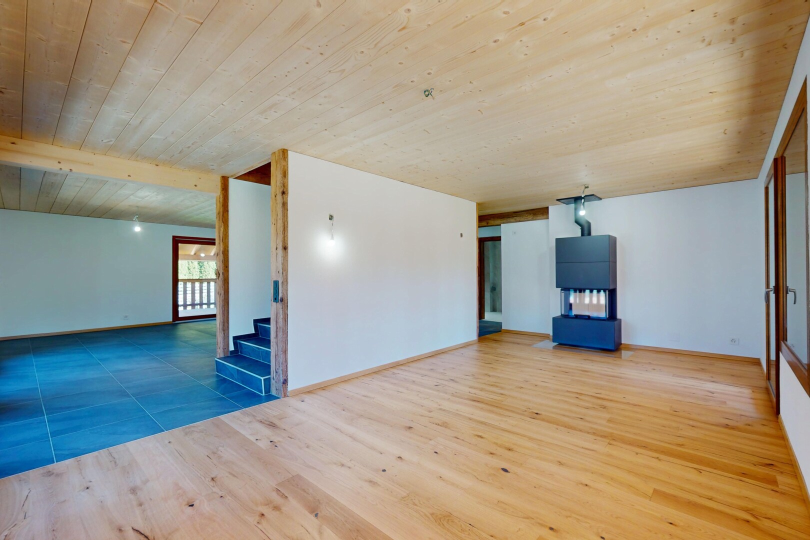 pièce vide avec cloison sèche, lumière naturelle, plafond en bois, et escaliers