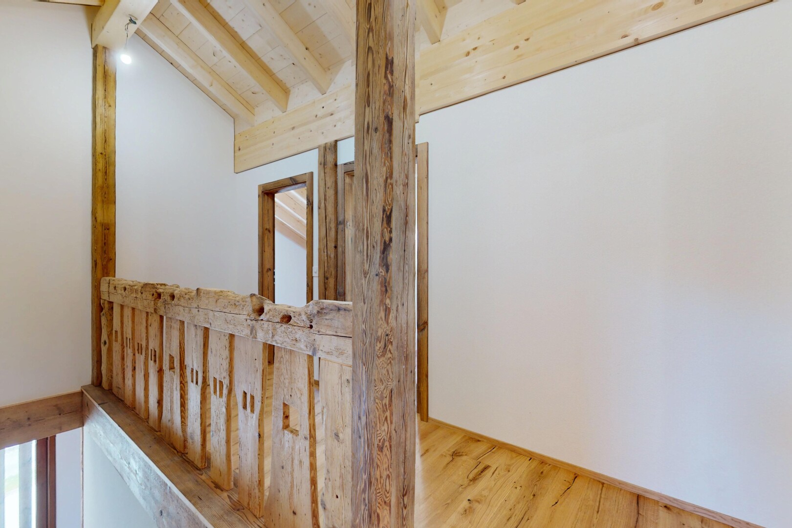 couloir avec cloison sèche, plafond voûté, plafond à poutres, et sol en finition bois